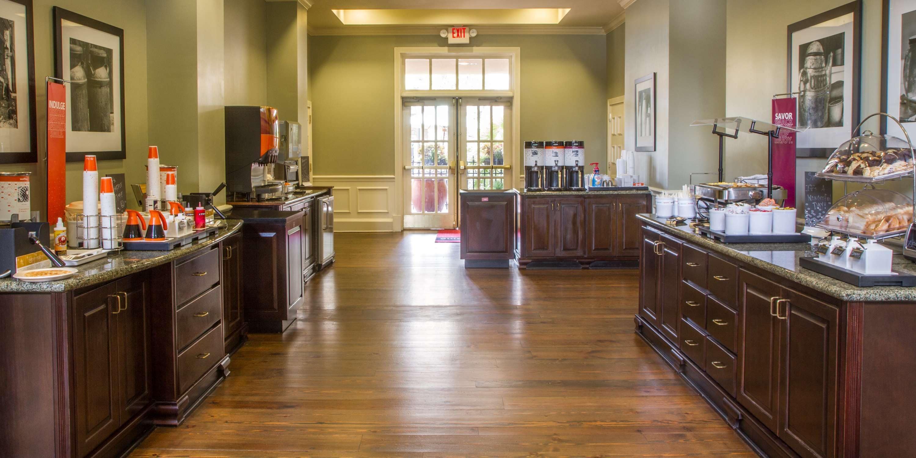 A hotel kitchen with wooden cabinets, a coffee station, and a buffet area.