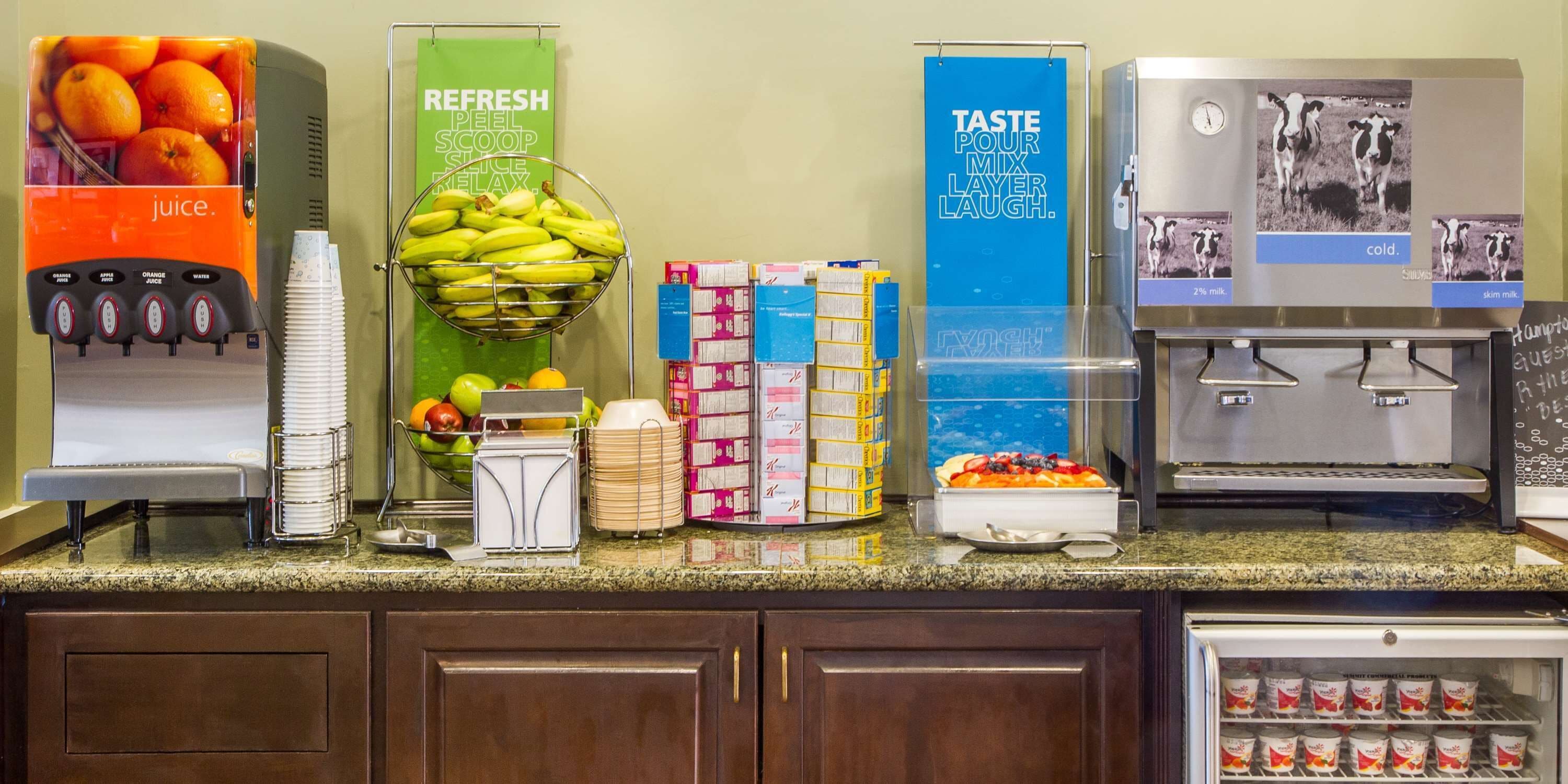 A buffet setup with juice dispensers, a fruit bowl, and various food items.