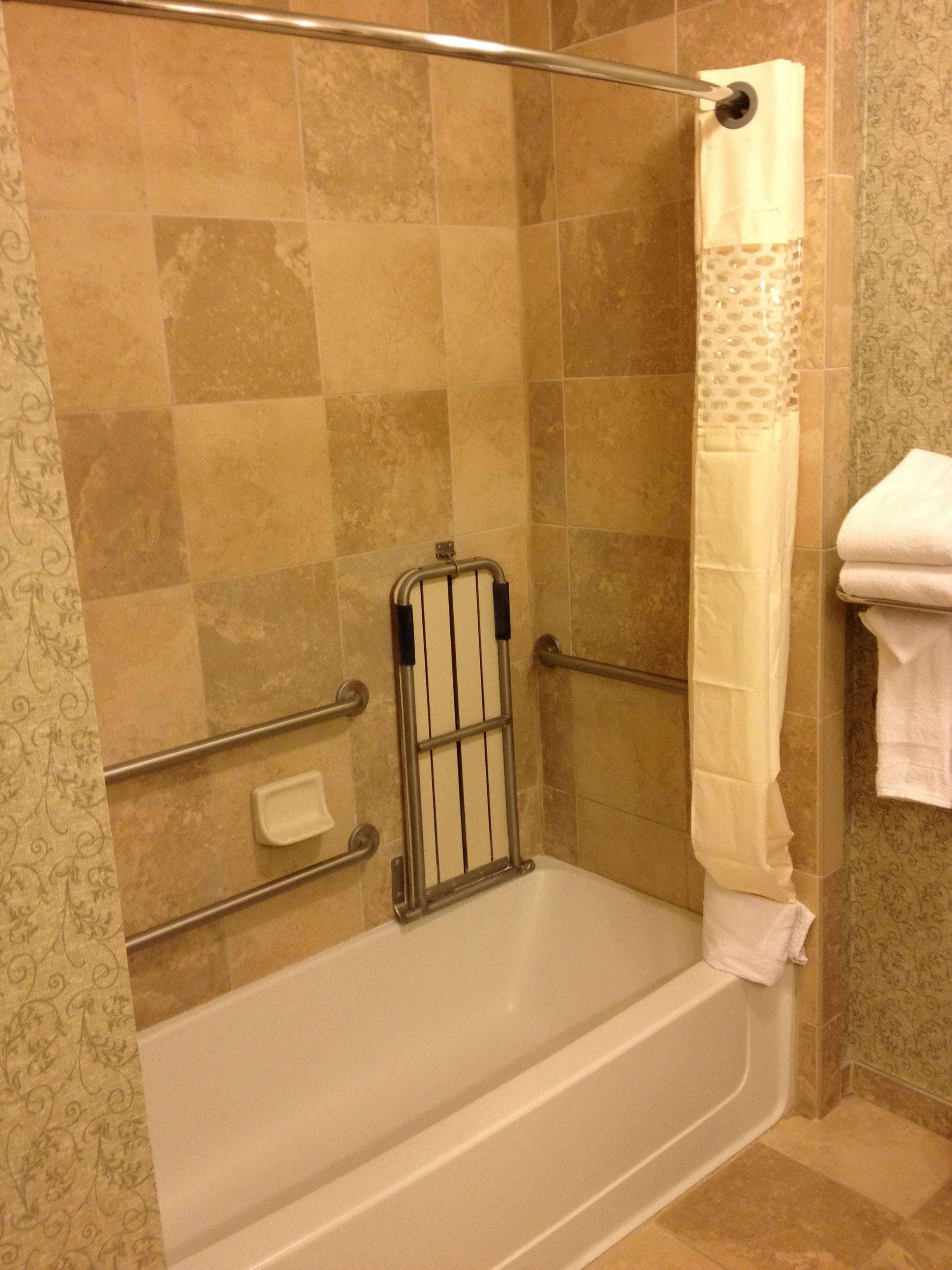 A shower area with a bathtub, grab bars, and a shower curtain.