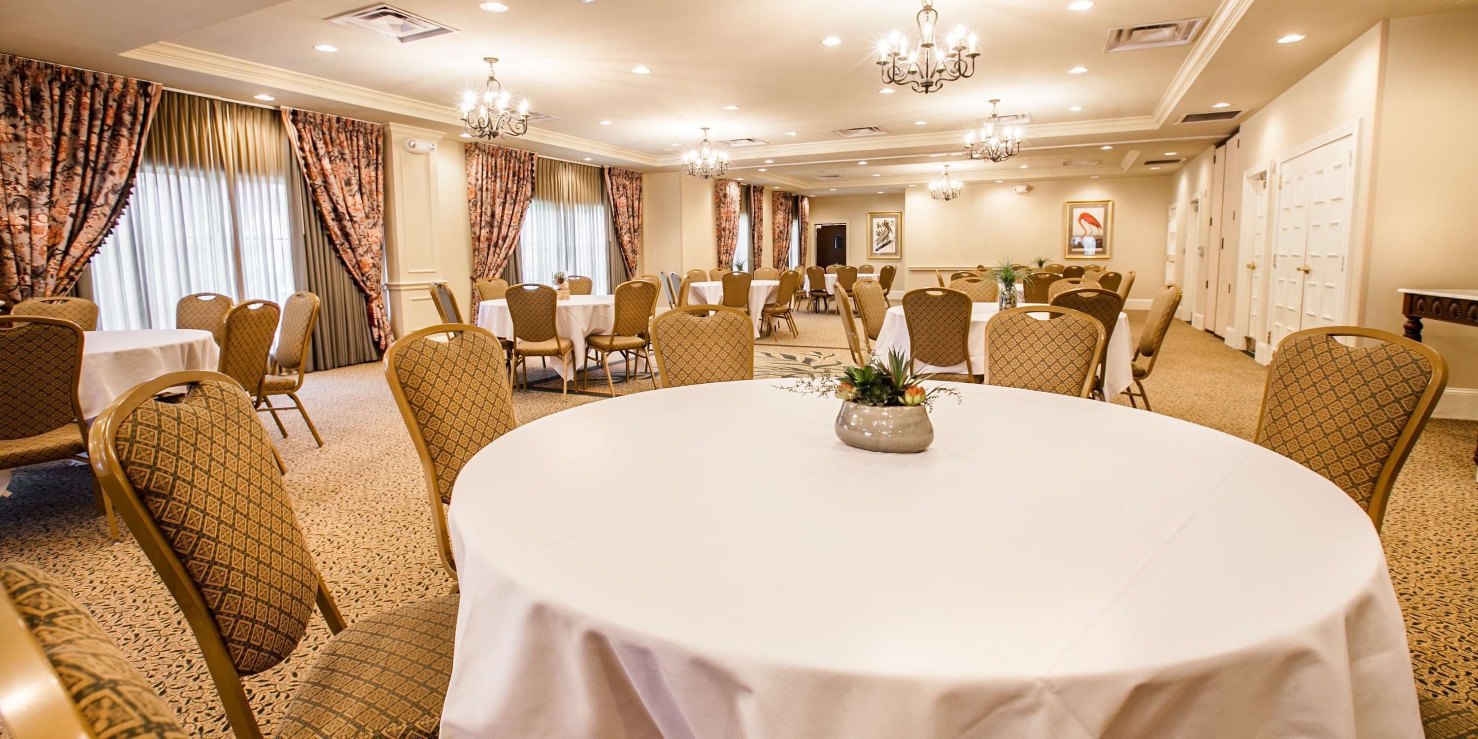 A conference room with round tables, chairs, and chandeliers.