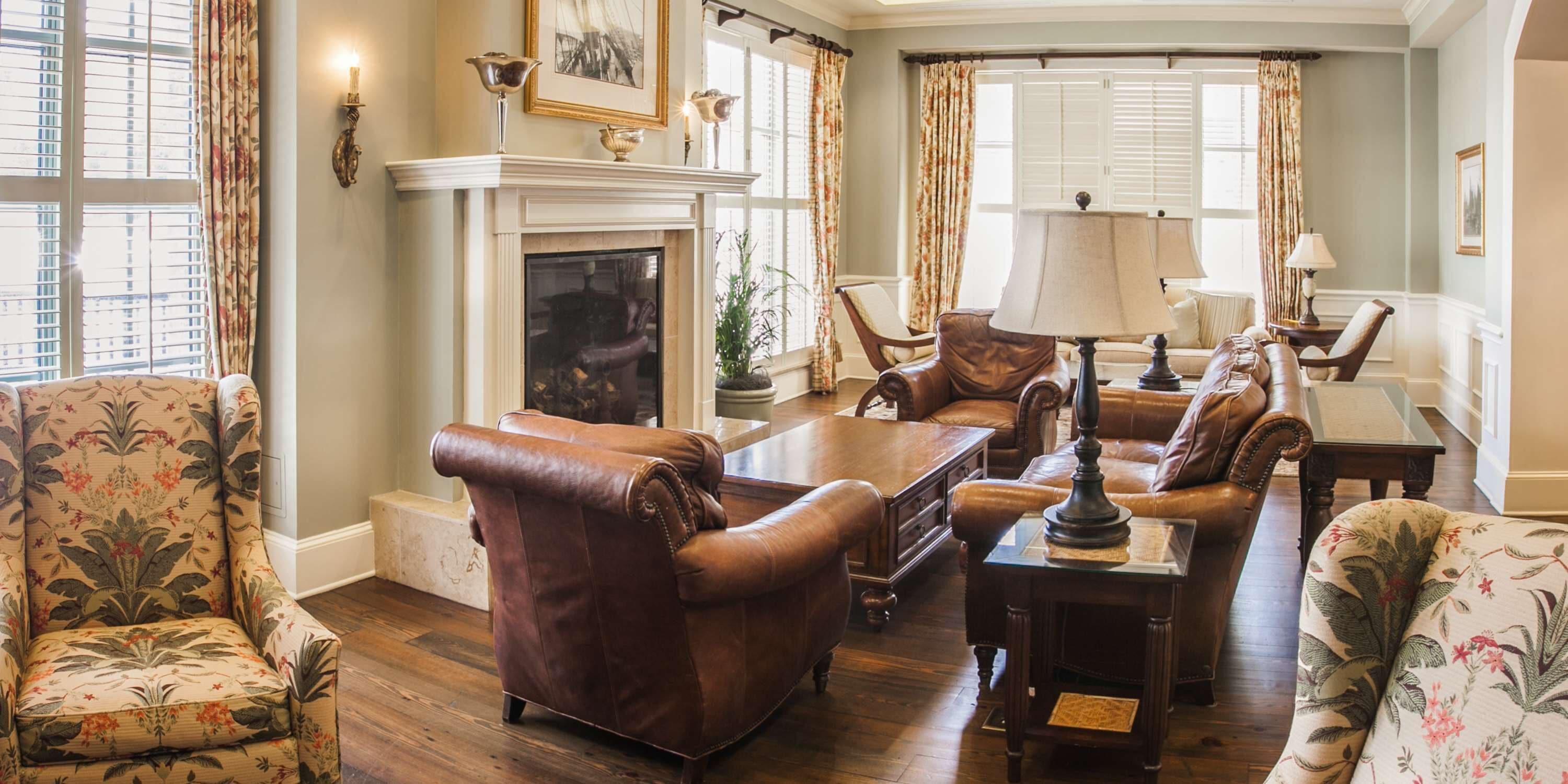 Un salon traditionnel avec des fauteuils en cuir, une cheminée et un coin repas comprenant une table et des chaises.