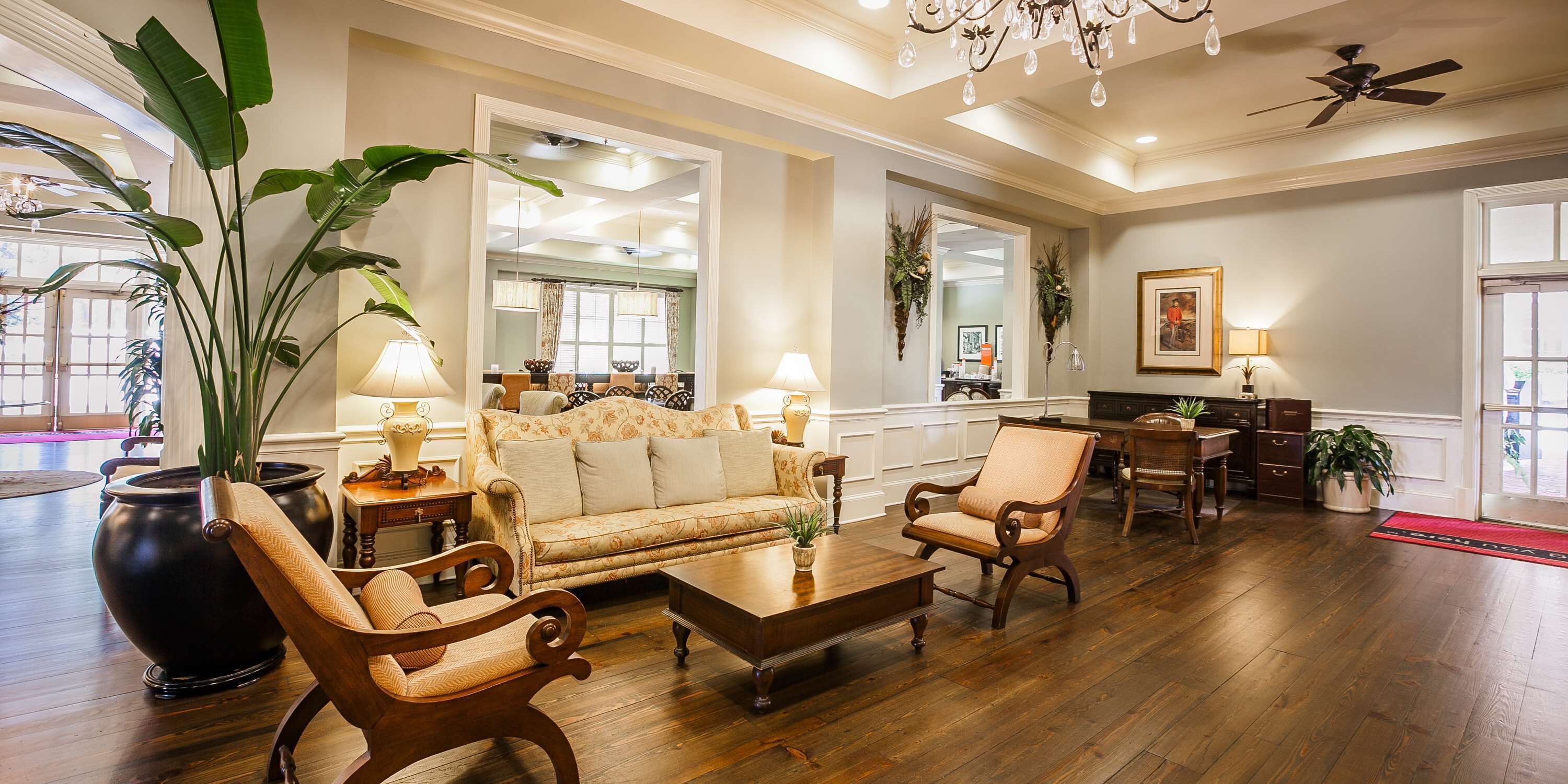 A spacious living room with a sofa, armchairs, a coffee table, and a dining area with a table and chairs.