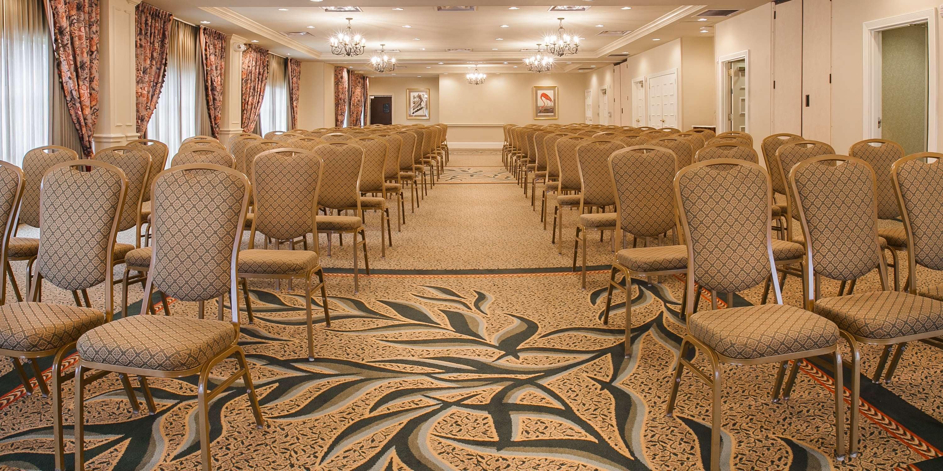 A conference room with rows of patterned chairs and a carpet with a leaf design.