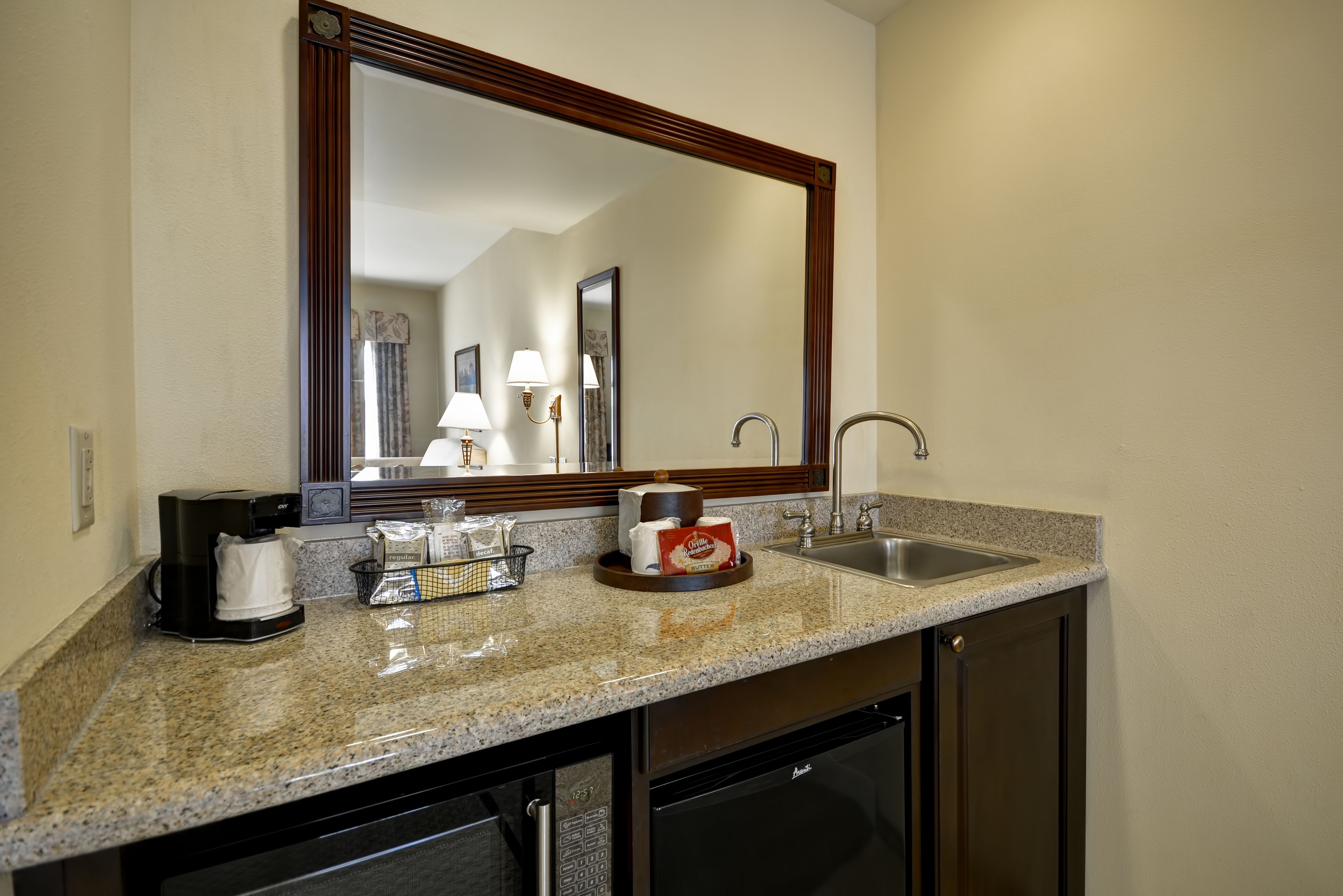 A kitchen with granite countertops, a coffee maker, a sink, and a dishwasher.