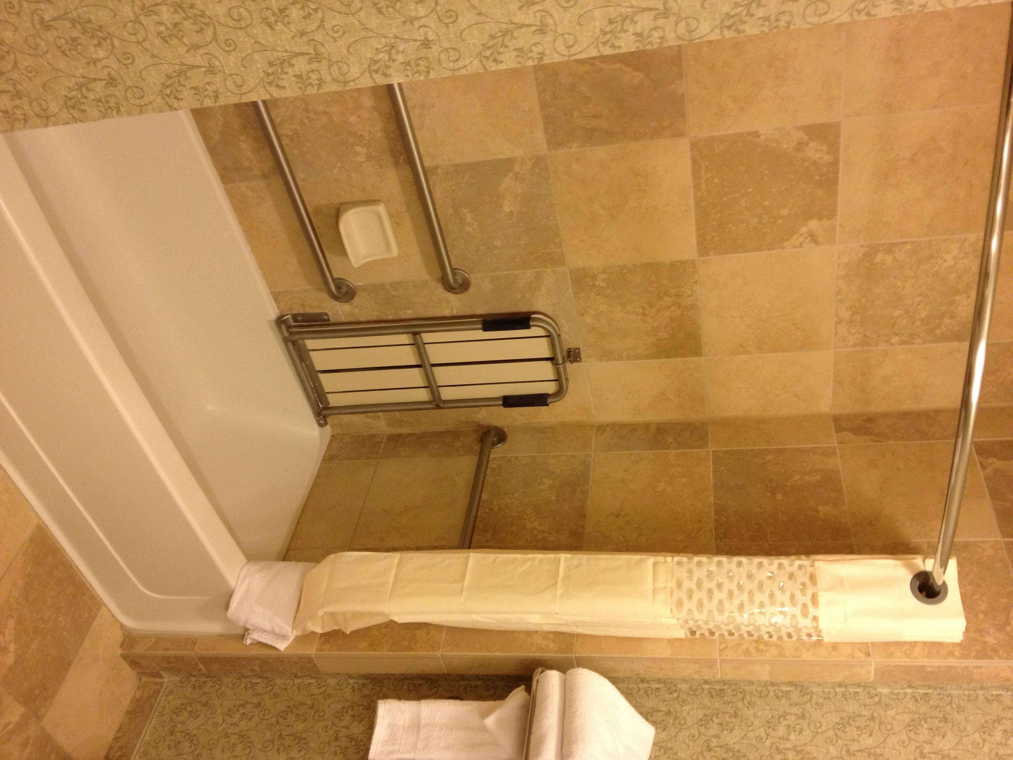 A shower area with a glass door, a metal towel rack, and a shower curtain.