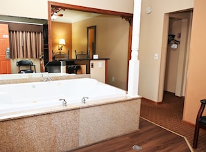 A bathroom with a large bathtub, a mirror, and a wooden floor. - Fellows Creek Lodge (Canton)
