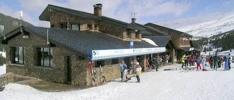 A stone building with a ski slope in front.