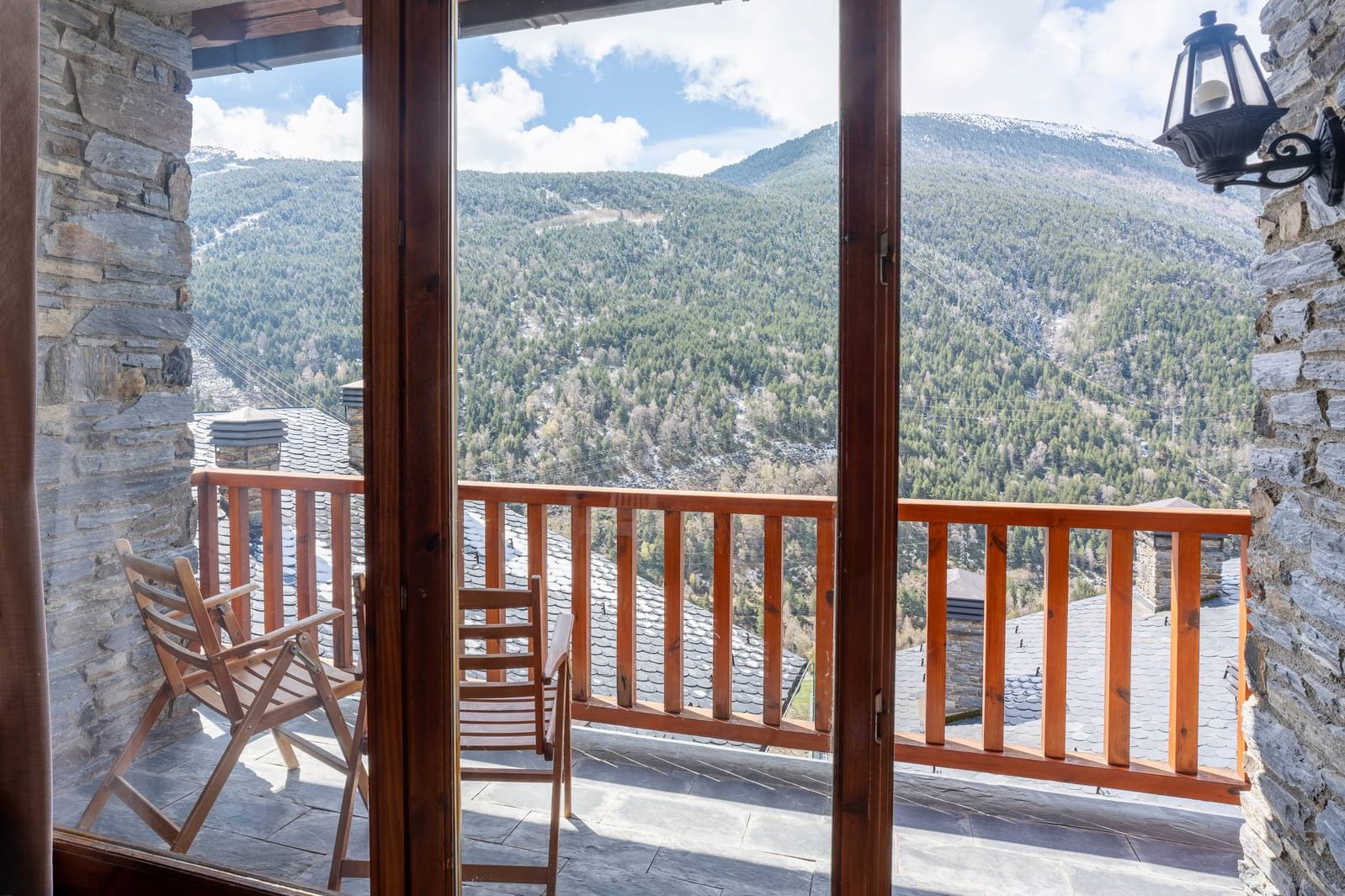 A balcony with a wooden railing, a chair, and a table.