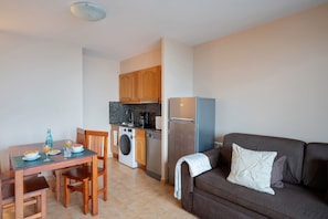 A compact living space with a dining area, kitchenette, and a sofa. - Apartamentos Ona Dorada el Tarter (Ransol)