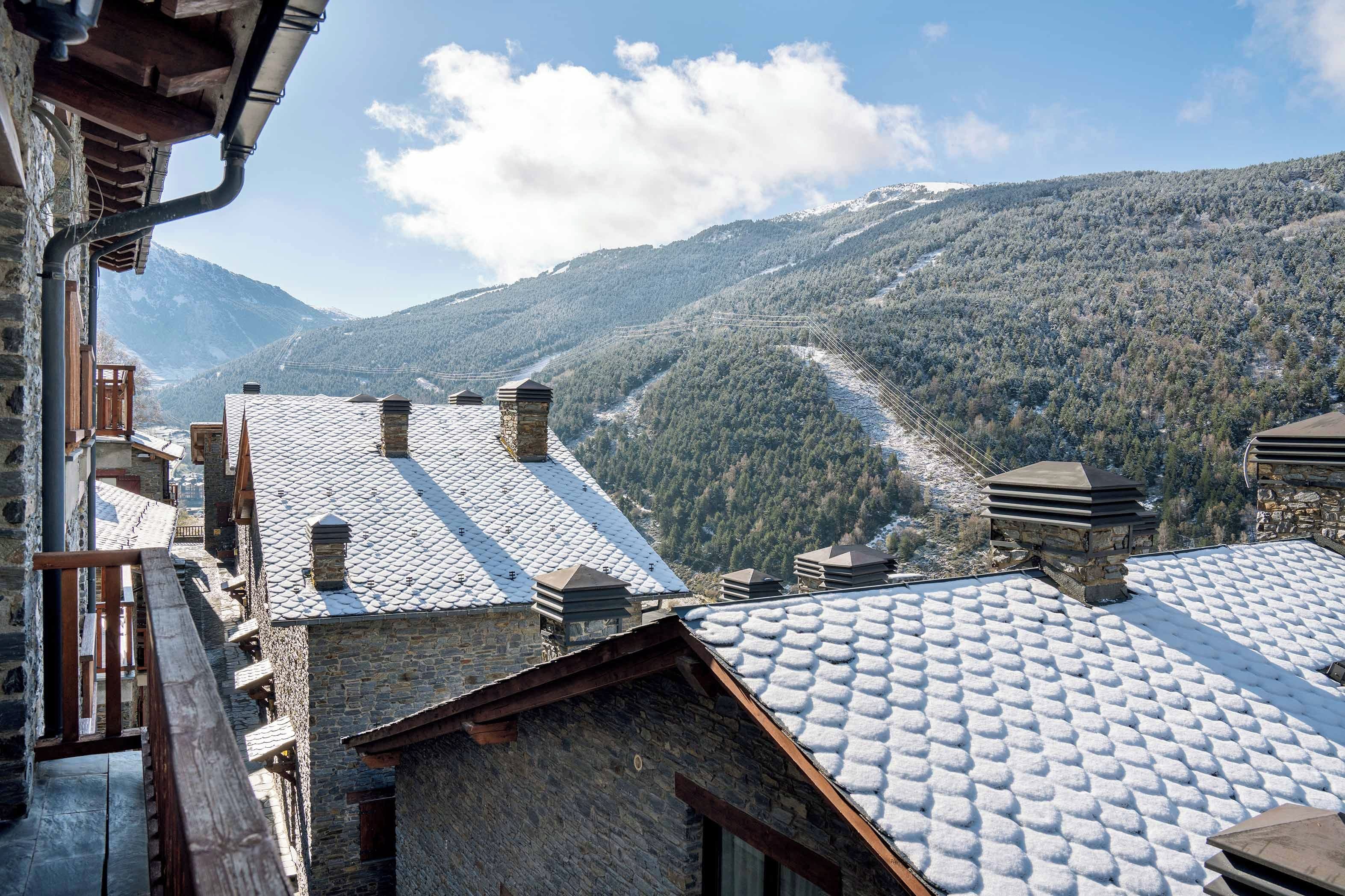 A mountainous landscape with snow-covered roofs and stone buildings, suggesting a winter setting.