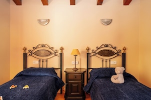 A bedroom with two beds, a nightstand with a lamp, and a teddy bear on one bed.