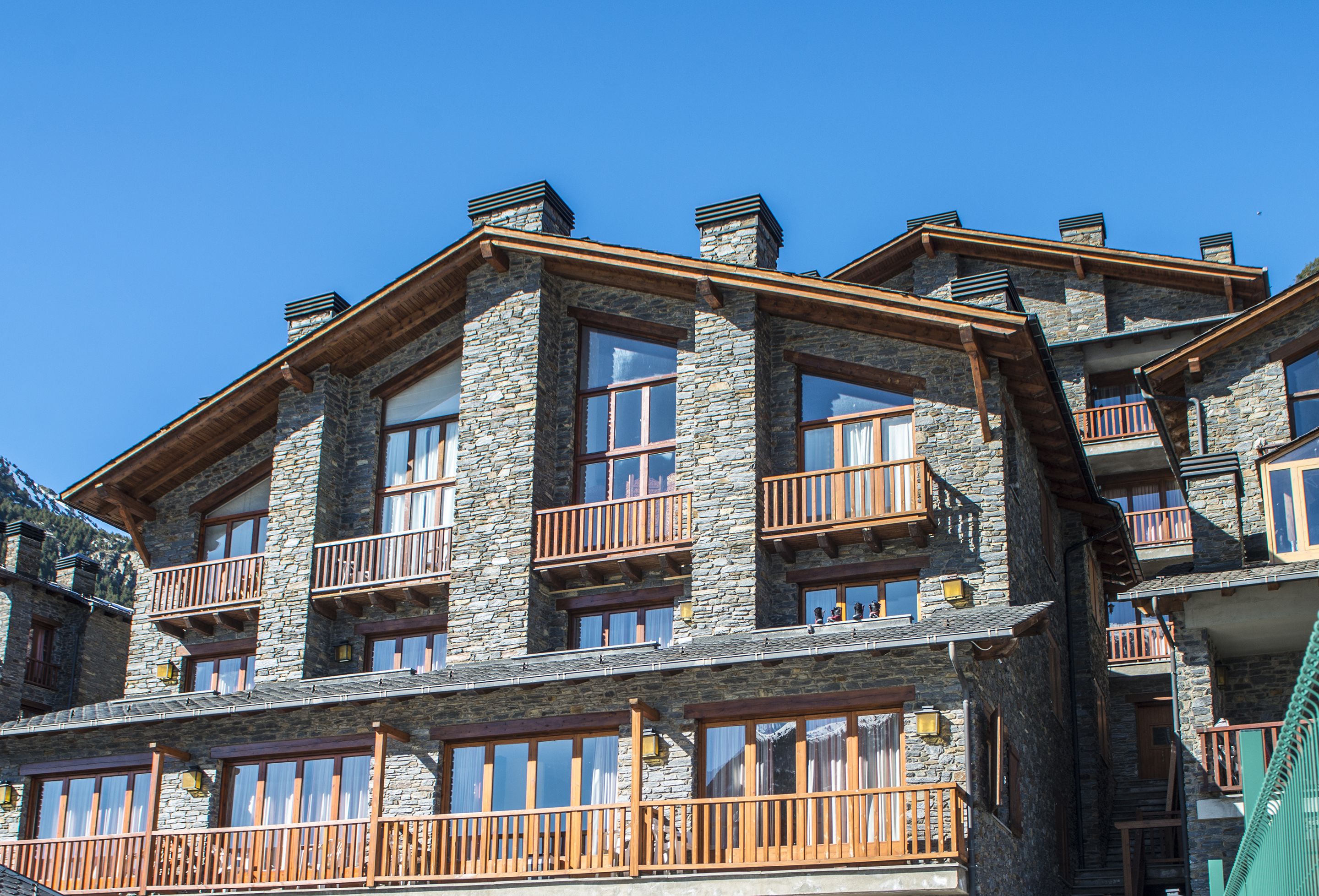 A multi-story stone building with balconies and large windows.