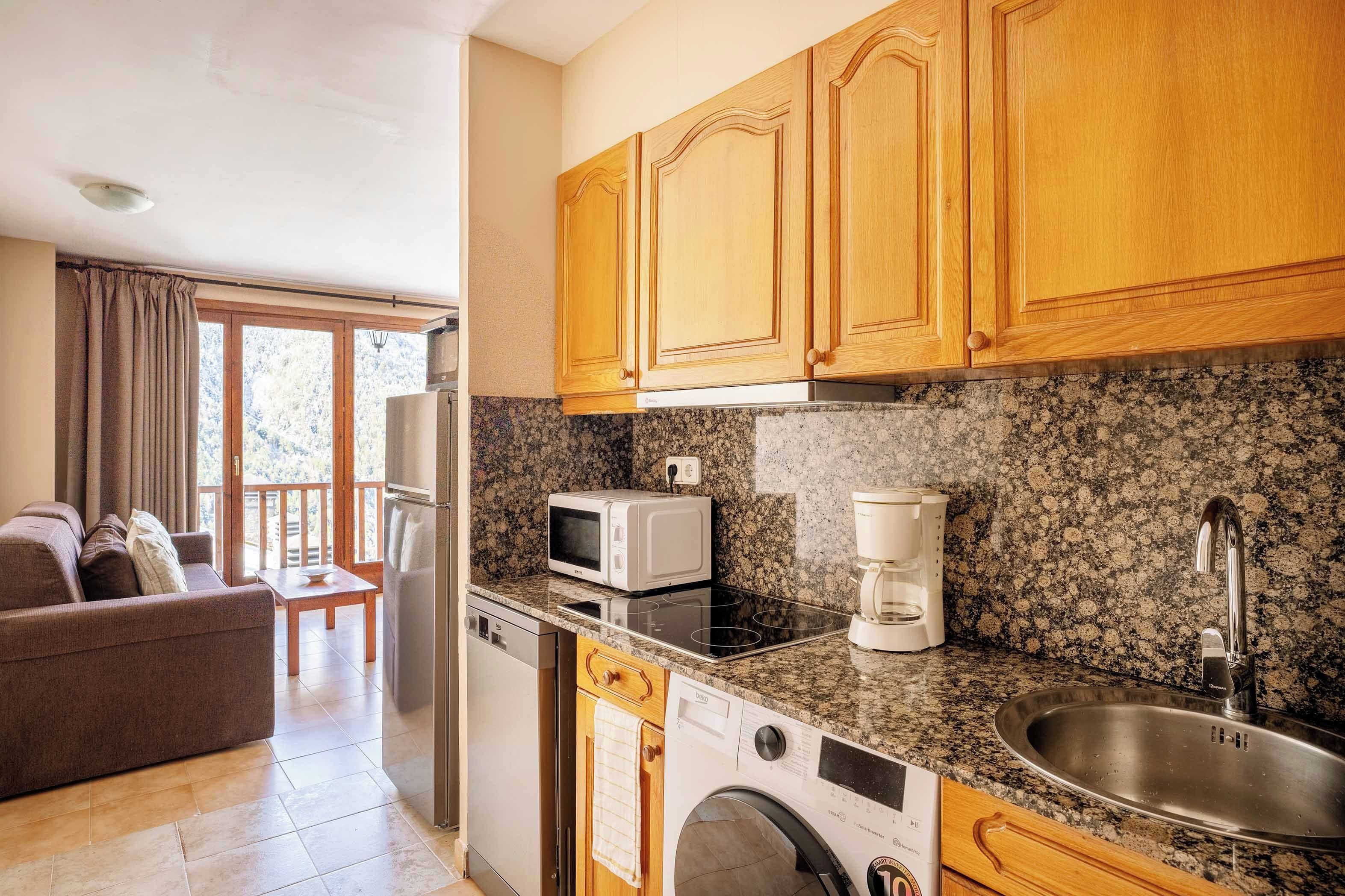 A compact kitchen with wooden cabinets, a microwave, a coffee maker, and a built-in washing machine.