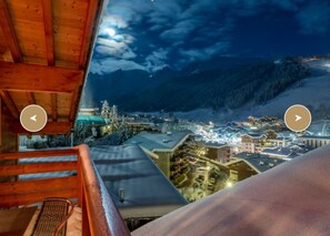 A view from a balcony overlooking a snowy mountain town at night.