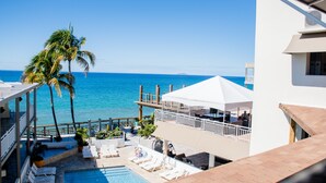 A pool area with lounge chairs and umbrellas, overlooking a clear blue sea. - Villa Cofresi Hotel (Rincon)