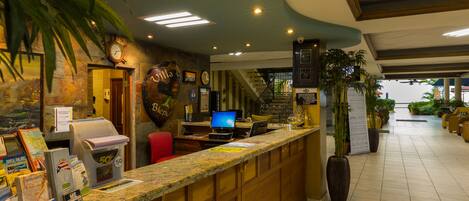 A reception area with a counter, computer, and a staircase leading to upper floors.