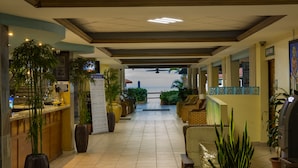 A hotel lobby with a reception desk, seating area, and potted plants. - Villa Cofresi Hotel (Rincon)