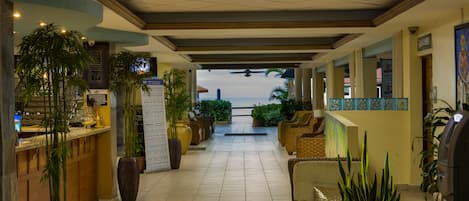 A hotel lobby with a reception desk, seating area, and potted plants.