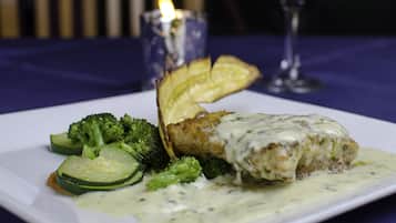 Een bord eten met een romige saus, broccoli en plakjes aardappel.