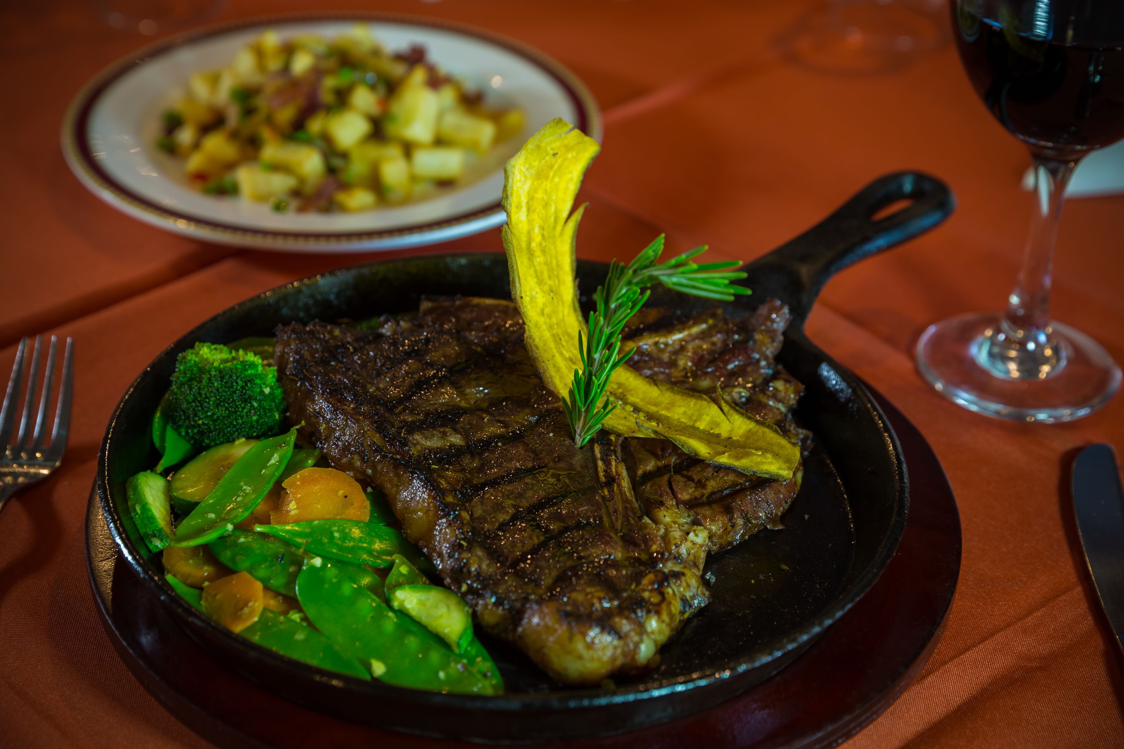 A steak with vegetables in a skillet on a table.