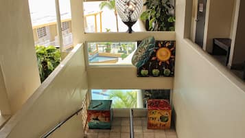 A staircase with a view of a pool and a balcony. There are colorful signs with messages and a decorative hanging light.