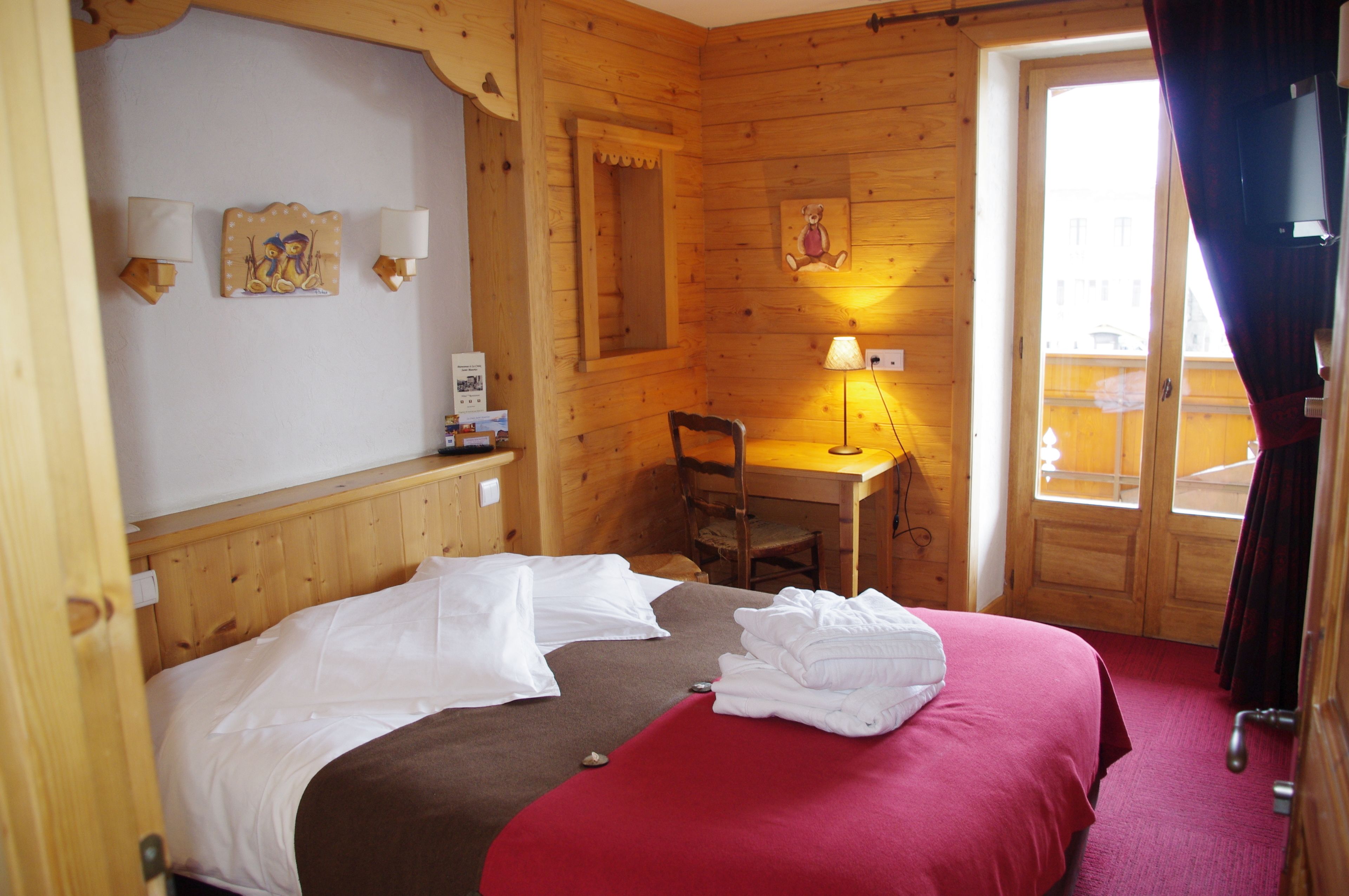 Una habitación de cabaña de madera con una cama, un escritorio y una silla.