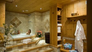 Een sauna met houten banken, betegelde muren en een bank met handdoeken en een tas.