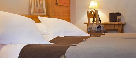 A hotel room with a bed, a wooden headboard, a nightstand with a lamp, a framed picture, and a small table with a bag and a glass.