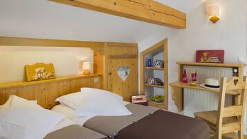 Traditional hotel room with a wooden headboard, bed, and nightstand, featuring a shelf and chair.