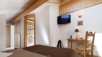 Une chambre à coucher avec un lit, un téléviseur fixé au mur, un bureau avec une chaise et une fenêtre.