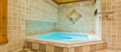 Un jacuzzi en una habitación con paredes de baldosas y techo de madera.