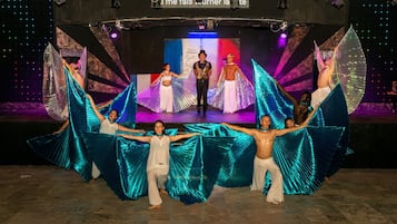 A stage with performers in costumes and a backdrop with text and lights.