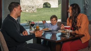 A dining table with plates of food, drinks, and a child.