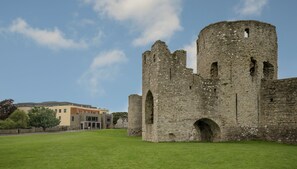 A historic stone castle with arched windows and a round tower, surrounded by a well-maintained lawn. - Trim Castle Hotel (Trim)