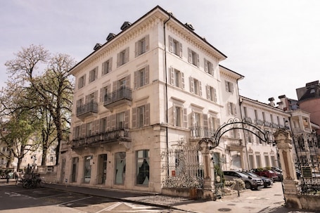A multi-story building with a classical facade, large windows, and a gated entrance.