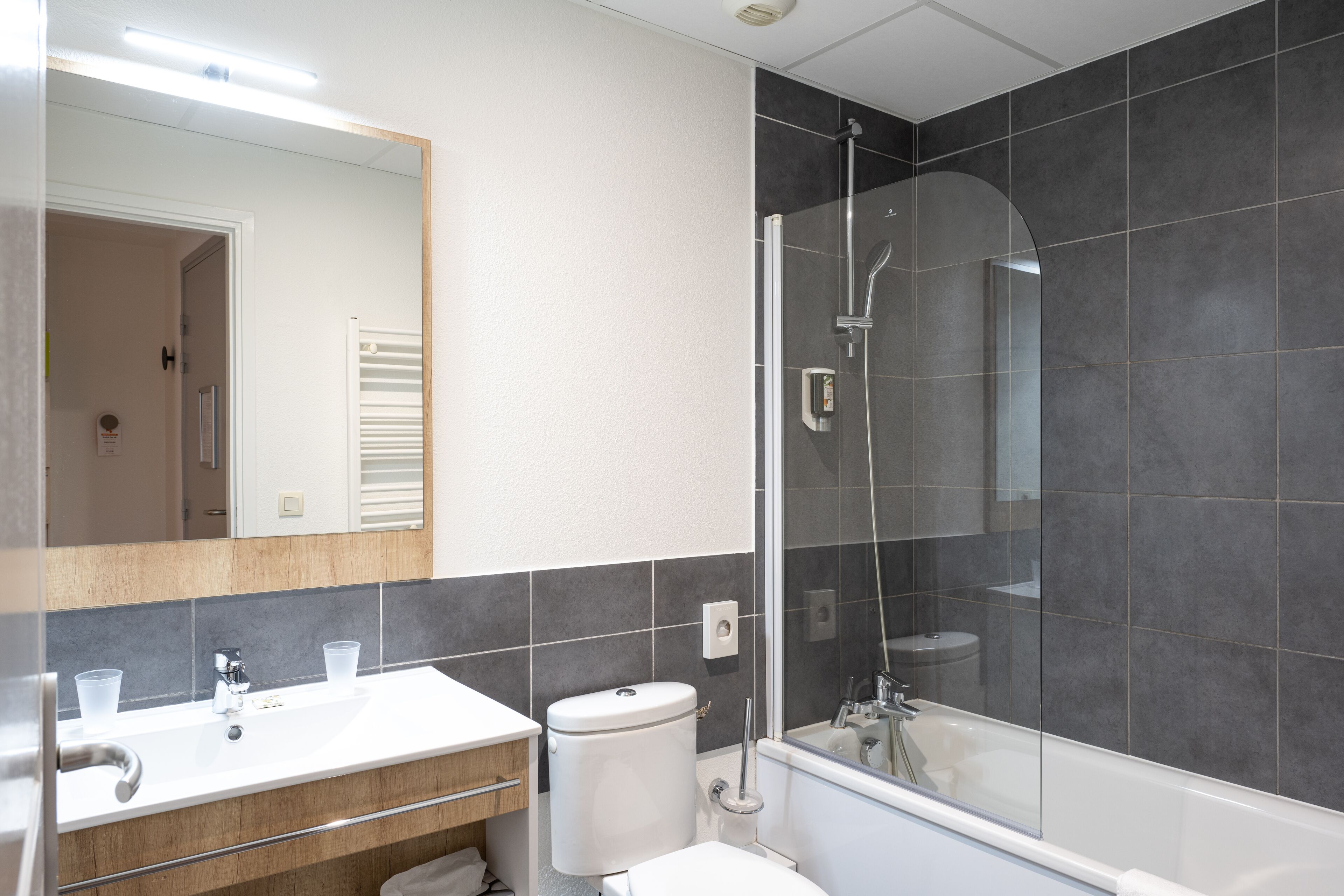 Ein modernes Badezimmer mit einer Duschkabine, einem weißen Waschbecken und einer Toilette.