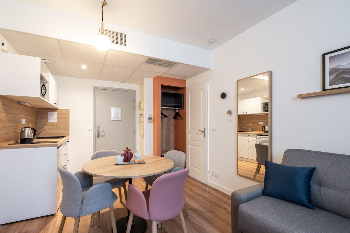 A compact living space with a dining area, kitchenette, and a seating area with a sofa and chairs.