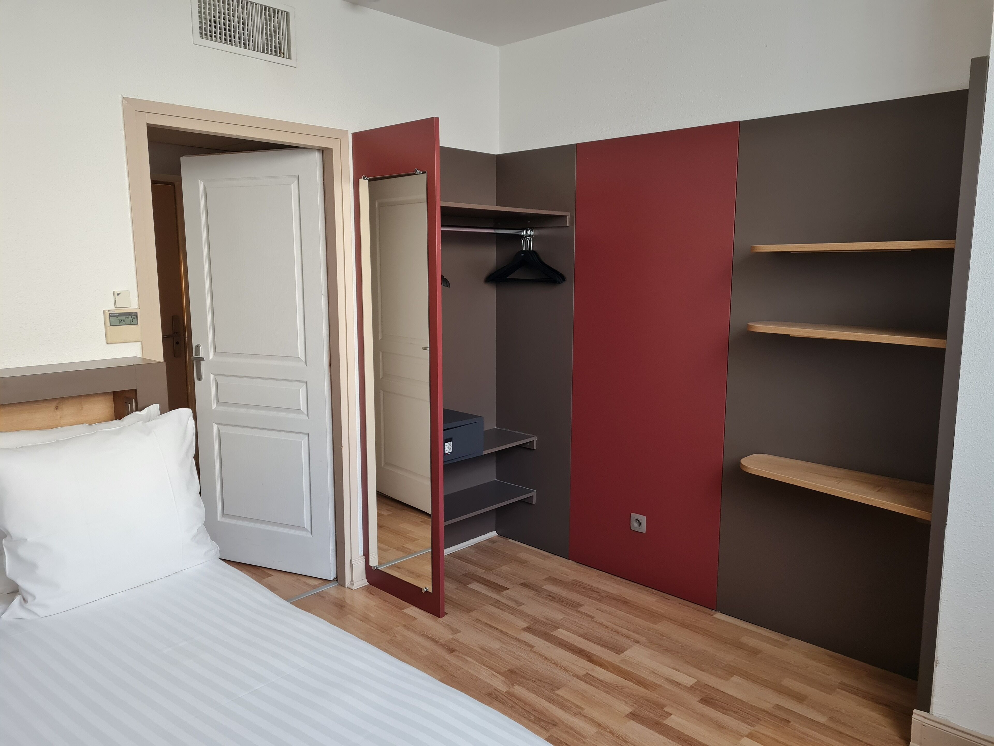 Un dormitorio con cama, armario y armario con estantes.