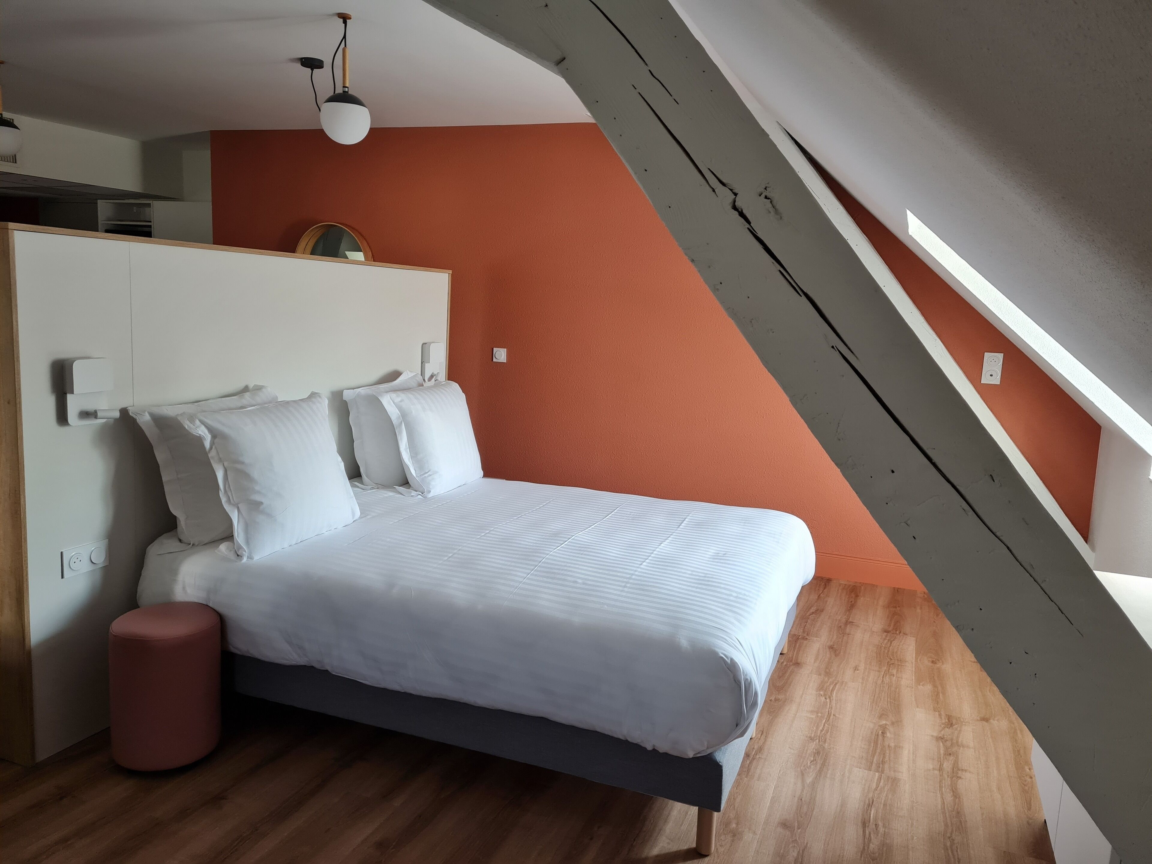 A bedroom with a bed, a bedside table, a lamp, and a window.