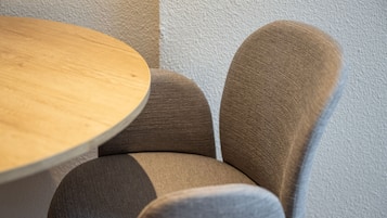 Una mesa redonda de madera con una silla tapizada en tono marrón.