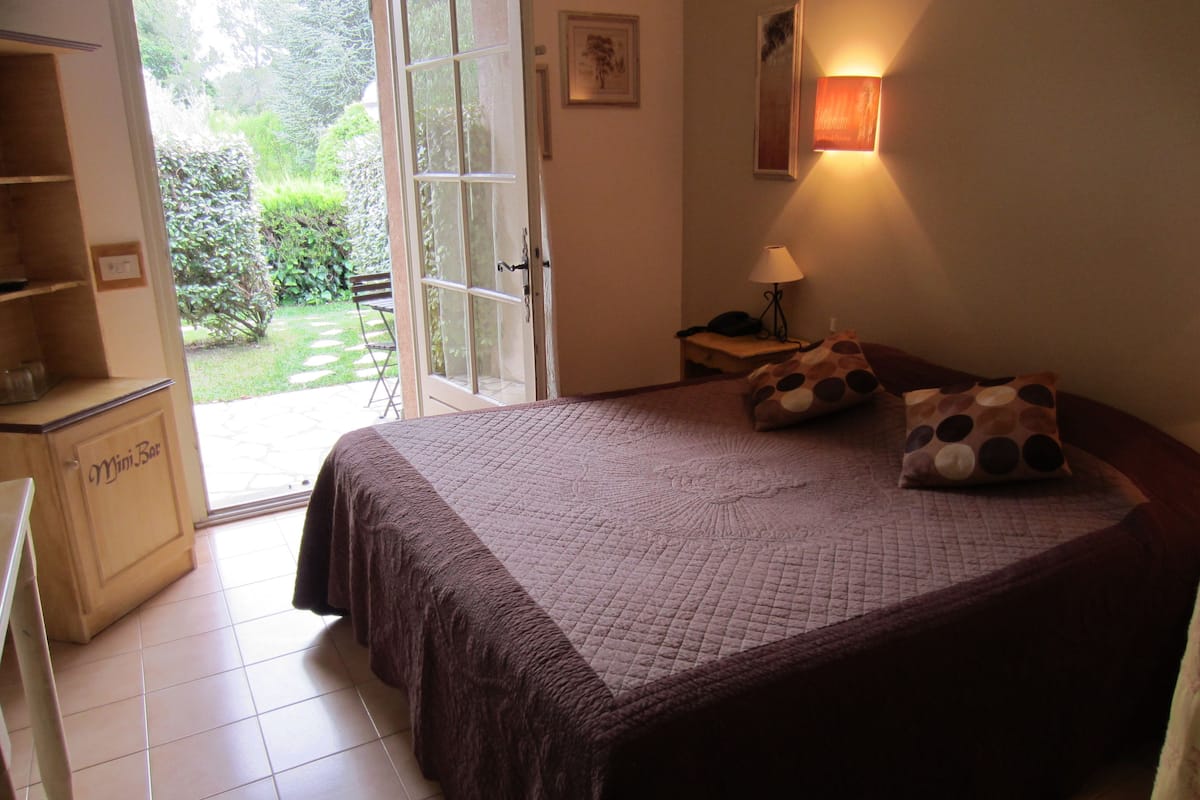 A bedroom with a bed, a nightstand, a lamp, and a Mini Bar.
