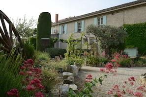 A garden with a gravel path, stone walls, and various plants and flowers. - Villa Glanum (St.-Rémy-de-Provence)