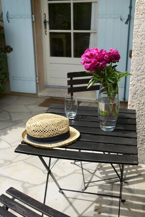 A black metal table with a straw hat and a vase of flowers.