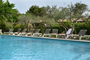 A swimming pool with lounge chairs and a fence.