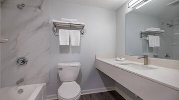 Un baño moderno con bañera, inodoro y un espejo grande.
