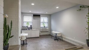 A modern kitchen with white cabinets, a built-in stove, and a window with blinds. - Motel 6 Franklin, OH (Franklin)