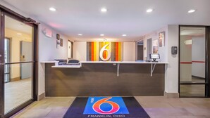 A hotel reception area with a large number '6' on the wall, a reception desk, and a mat with '6 Franklin, Ohio' on it. - Motel 6 Franklin, OH (Franklin)