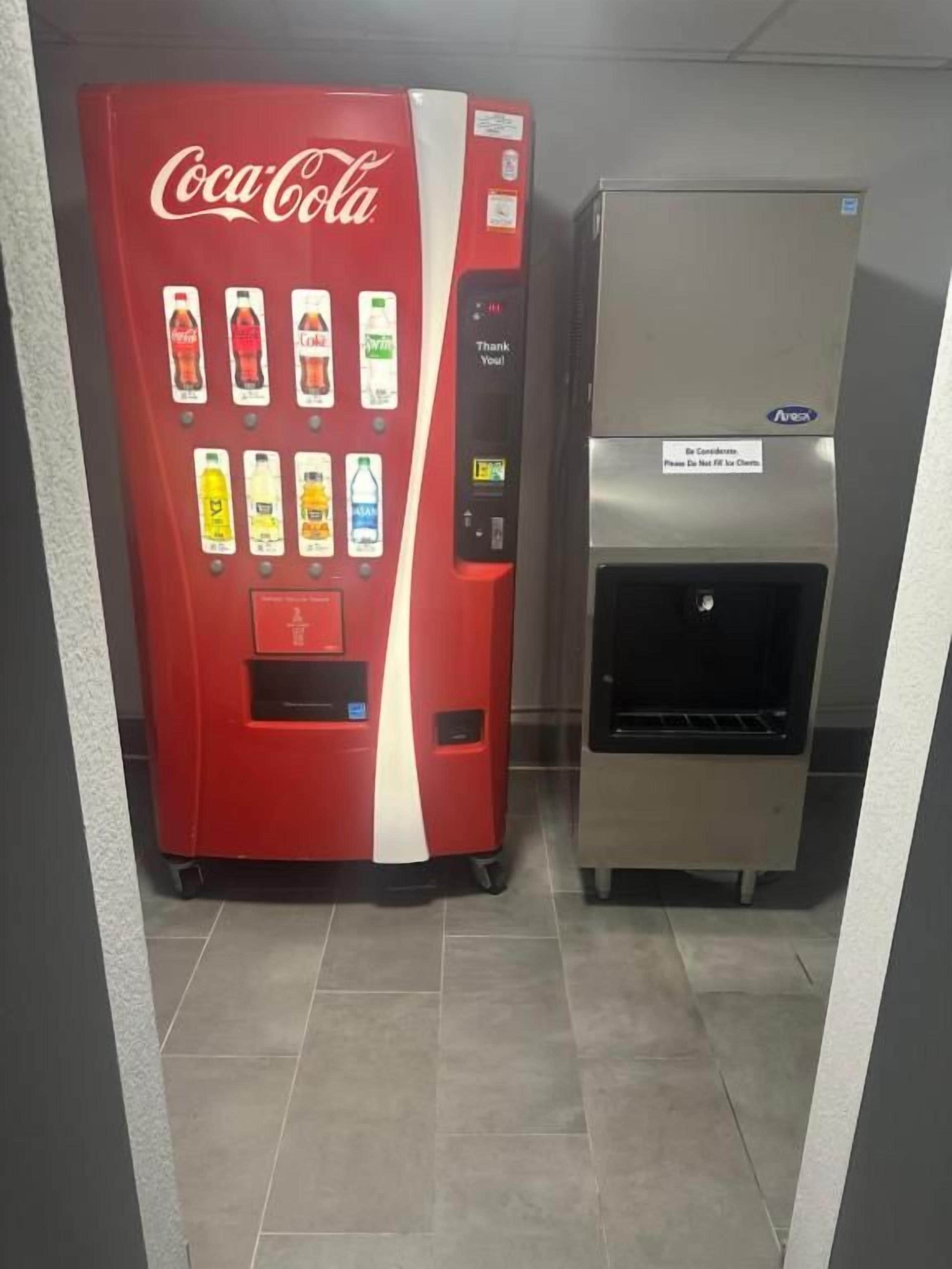 A vending machine with a Coca-Cola logo and a silver appliance with a sign that says 'Please Be Careful.'