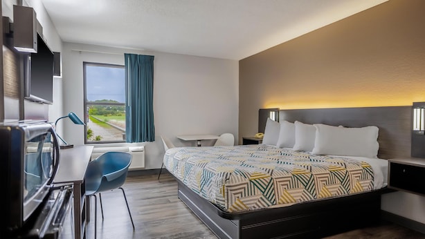 A modern hotel room with a bed, desk, and chair, a TV, and a large window with a view. - Motel 6 Franklin, OH (Franklin)