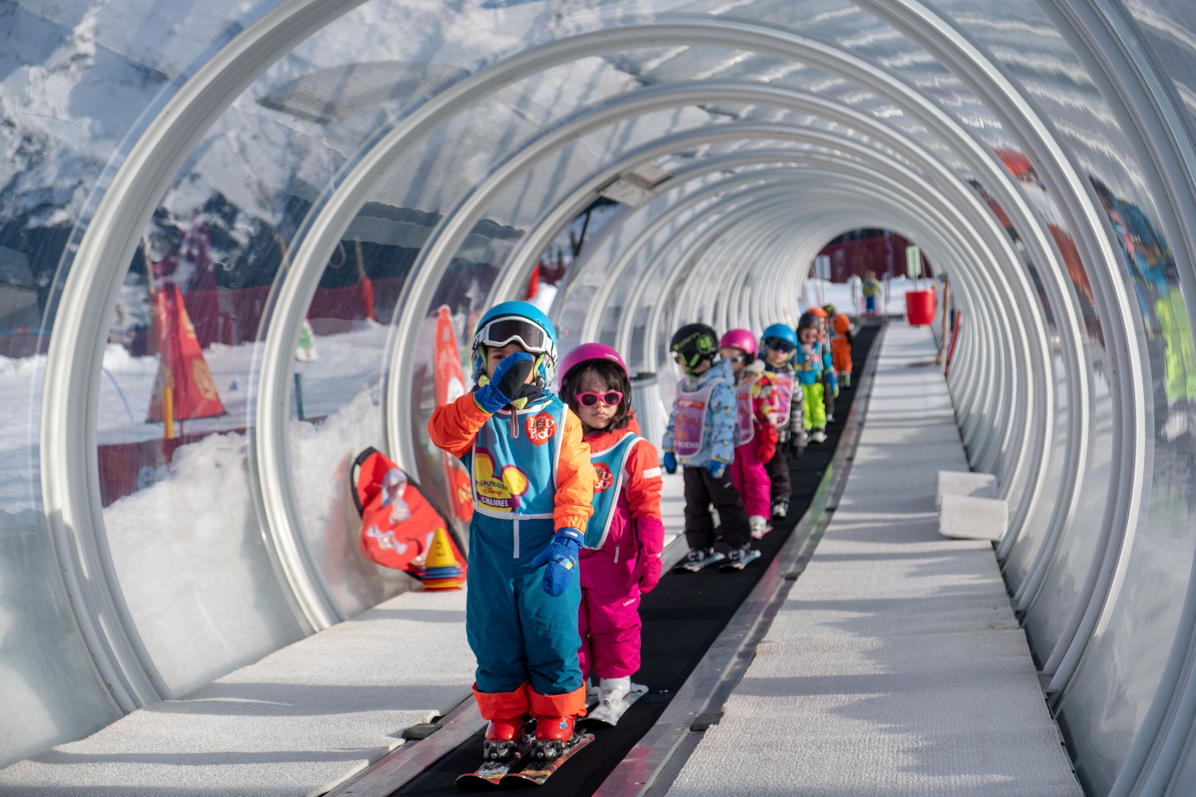 A tunnel with a snowy landscape and a group of people in colorful winter clothing.